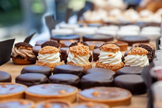 Vitrine de pâtisseries variées avec des gâteaux décorés et des douceurs crémeuses sur une table en bois.
